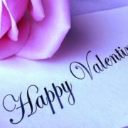 Happy Valentine's Day written on a note with a pink rose